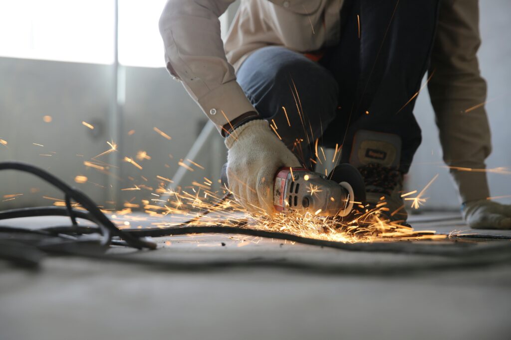 pexels-photo-1216544-1216544 A skilled industrial worker uses a grinder creating a burst of sparks indoors.